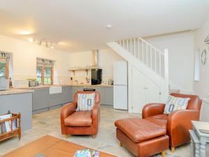 a living room with two chairs and a kitchen at Moorhen Cottage in Hollingbourne