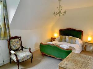 a bedroom with a bed and a chair and a table at Moorhen Cottage in Hollingbourne