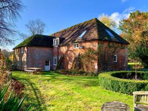 Moorhen Cottage في Hollingbourne: منزل من الطوب الأحمر القديم مع ساحة عشبية