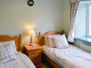 a bedroom with two beds and a lamp on a night stand at Regina Cottage in Bradpole
