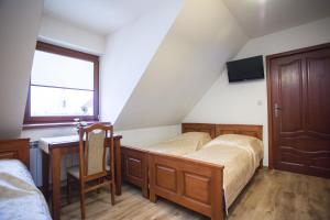 a bedroom with a bed and a desk and a window at U Gruloka in Poronin