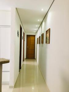 a hallway with white walls and a wooden door at Casa moderna de praia em Itaipuaçu RJ in Maricá