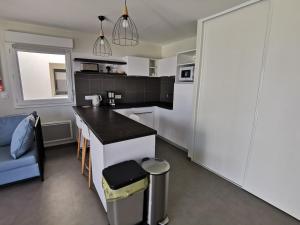 a kitchen with a black counter and a white refrigerator at Appartement cosy côté cour, accès plage, piscine, balcon, parking, animaux admis, La Tranche-sur-Mer - FR-1-194-228 in La Tranche-sur-Mer