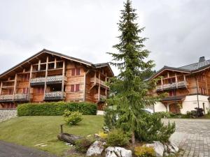 a pine tree in front of a large building at Spacieux T4 proche des pistes avec terrasse et parking - 6-8 pers. - FR-1-685-22 in Les Gets