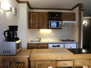 a kitchen with wooden cabinets and a counter top with a microwave at Appartement Aussois, 3 pièces, 6 personnes - FR-1-508-276 in Aussois