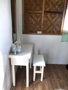 a white table and a stool next to a wall at MIOKI HOMETEL in Batuan