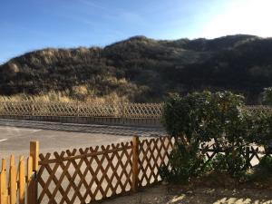 une clôture sur une route avec une montagne en arrière-plan dans l'établissement Maison à 50m de la Plage avec Terrasse, 2 Chambres et Parking Privé - Fort-Mahon-Plage - FR-1-482-35, à Fort-Mahon-Plage