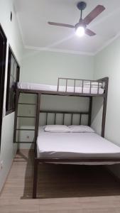 a bedroom with two bunk beds and a ceiling fan at Pousada Menina Moça in Olímpia