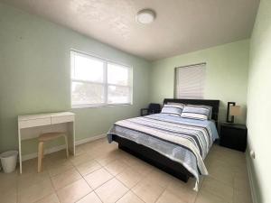 a bedroom with a bed and a desk and two windows at Sunset Charlotte - Home away from home in Port Charlotte