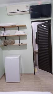 a room with a tv and a white refrigerator at Pousada Menina Moça in Olímpia