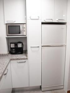 uma cozinha com armários brancos, um frigorífico e um micro-ondas em ApartUP La Concha Beachfront I em Oropesa del Mar