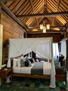 1 dormitorio con 1 cama grande con dosel en Umakayu Joglo Villa Canggu - Boutique Hotel, en Canggu