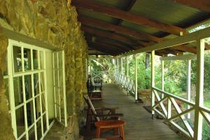 um alpendre de madeira com cadeiras e uma parede de pedra em Reilly's Rock Hilltop Lodge em Lobamba