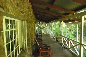 a wooden porch with chairs and a stone wall at Reilly's Rock Hilltop Lodge in Lobamba