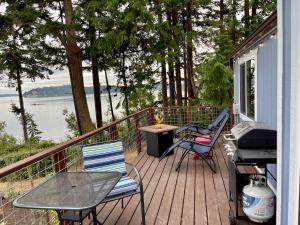 una terraza con mesa, sillas y parrilla en Private Beach - Port Ludlow Beach Cottage on Puget Sound en Port Ludlow