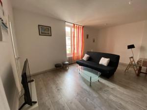 ein Wohnzimmer mit einem schwarzen Sofa und einem Glastisch in der Unterkunft Appartement 57m² avec WIFI à 200m des Thermes – 4 pers. – Parking gratuit – La Roche-Posay - FR-1-541-40 in La Roche-Posay