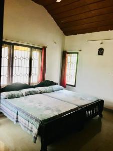 a bedroom with a large bed in a room with windows at La Paz Coorg homestay at Madikeri town in Madikeri