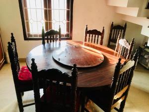 a wooden dining room table with chairs and a large wooden table at La Paz Coorg homestay at Madikeri town in Madikeri