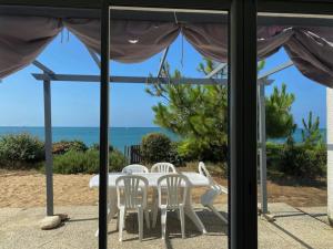a table and chairs on a patio with a view of the ocean at Maison vendéenne rénovée, accès direct plage, terrasses, BBQ, parking gratuit - FR-1-336-123 in Longeville-sur-Mer +12 photos