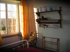 a bedroom with a bed and two chairs and windows at B&B "Les Remparts" in Vouvant