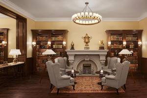 a library with a fireplace and chairs and a chandelier at Sawai Man Mahal in Jaipur