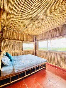 Cama en habitación con techo de madera en Bamboo Villa en Gia Nghĩa