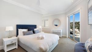 a white bedroom with a large bed and a window at Unit 52 - 4 Bed Platinum Ocean View in Terrigal