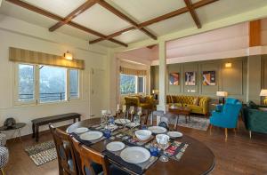a dining room with a table and a living room at StayVista at Eastbury in Mashobra