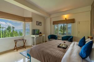 a bedroom with a bed with blue pillows and a window at StayVista at Eastbury in Mashobra