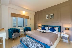 a bedroom with a bed and blue chairs and a desk at StayVista at Eastbury in Mashobra