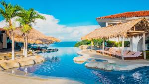 a resort infinity pool with chairs and umbrellas at Condovac La Costa All Inclusive in Playa Hermosa