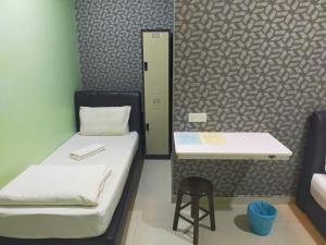 a room with two beds and a table and a stool at Leaf Guest House in Kuantan