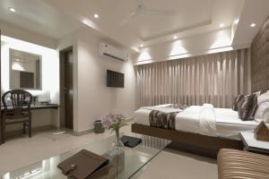 Hotel Ariana Residency في مومباي: غرفة نوم بسرير ومكتب واريكة
