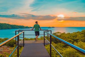 a man walking down a stairway with the sunset in the background at Condovac La Costa All Inclusive in Playa Hermosa