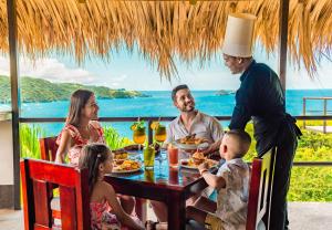 a group of people sitting around a table eating food at Condovac La Costa All Inclusive in Playa Hermosa