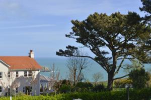 een wit huis met een boom op de voorgrond bij Saints Bay Hotel in St Martin Guernsey