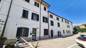 un bâtiment blanc avec volets noirs dans une rue dans l'établissement 1 Bardo House, à Bardolino