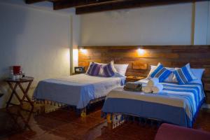 a hotel room with two beds and a table at Arte Sano Hotel San Cristobal in San Cristóbal de Las Casas