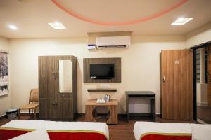 ティルパティにあるDLR GRANDのベッド2台とテレビが備わるホテルルームです。
