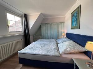 a bedroom with a bed with a blue headboard and a window at Meer-Lust-Sylt sea cottage in Westerland (Sylt)