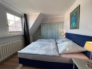 Schlafzimmer mit einem Bett mit blauem Kopfteil und einem Fenster in der Unterkunft Meer-Lust-Sylt sea cottage in Westerland
