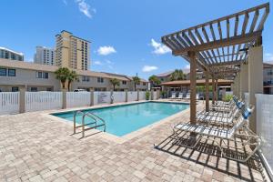 a swimming pool with chairs and a wooden pergola at Sugar Beach D17 in Navarre