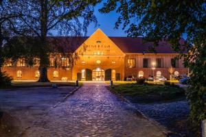 un gran edificio de ladrillo por la noche con entrada en Hotel Breitenburg, en Breitenburg