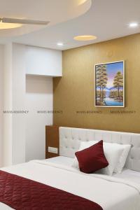 a bedroom with a large white bed with a red pillow at Moois Residency ,Bangalore in Bangalore