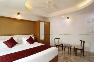 a hotel room with a large bed and a chair at Moois Residency ,Bangalore in Bangalore