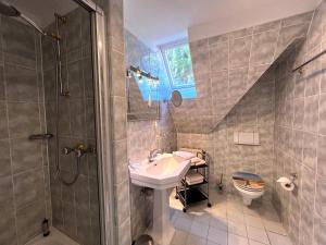 ein Bad mit einem Waschbecken, einer Dusche und einem WC in der Unterkunft Meer-Lust-Sylt sea cottage in Westerland
