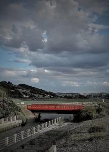 a red train crossing a bridge over a river at Maison chaleureuse et lumineuse à 400m de la plage in Veulettes-sur-Mer