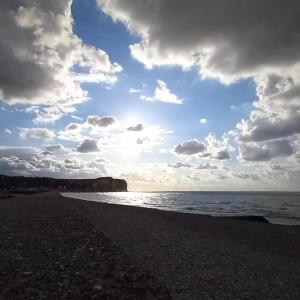 a beach with a cloudy sky and the ocean at Maison chaleureuse et lumineuse à 400m de la plage in Veulettes-sur-Mer
