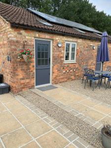 a brick house with a door and a table and an umbrella at Mowbray Stable Cottages in Thirsk