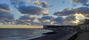 a beach with a cloudy sky and the ocean at Maison chaleureuse et lumineuse à 400m de la plage in Veulettes-sur-Mer